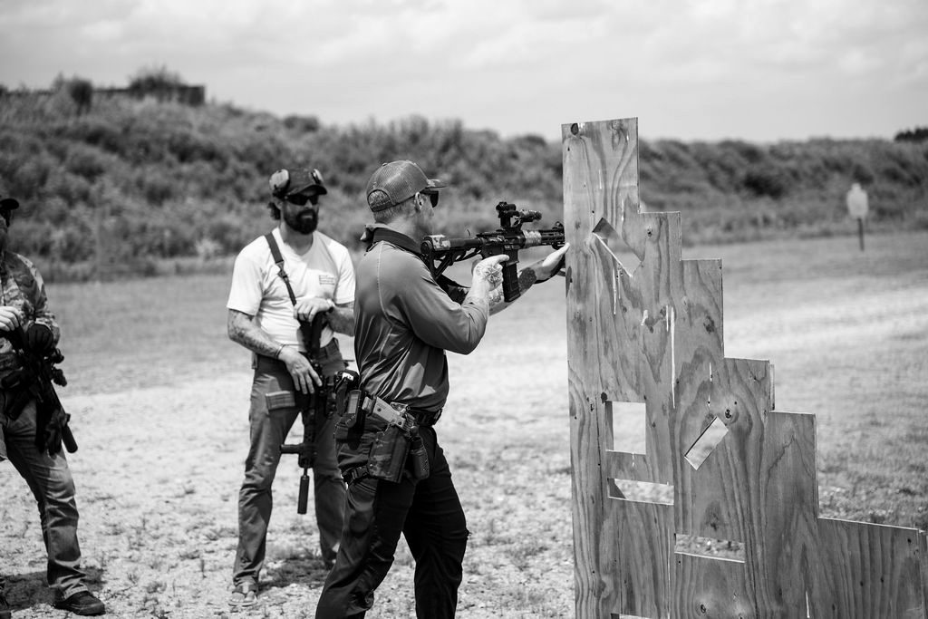 An instructor coaching a student on a carbine at a wooden barricade